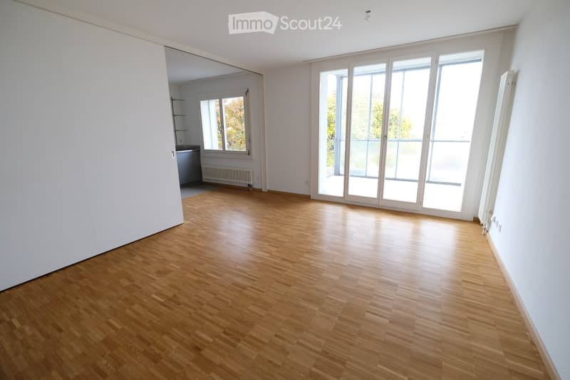 Completely empty room with wooden flooring, large windows, and white walls. No furniture or equipment.