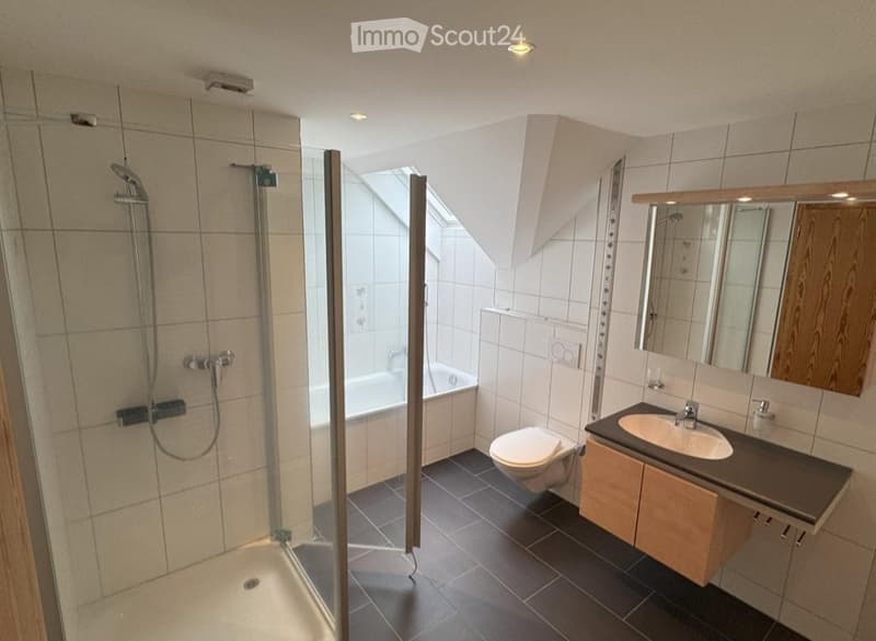 Modern bathroom with a glass-enclosed shower, bathtub, toilet, sink, and a large mirror above the sink.