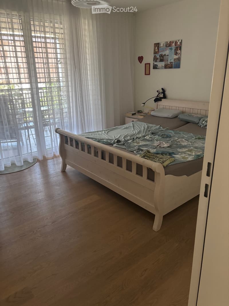 A well-lit bedroom with a wooden bed, nightstand, and decorative items on the wall.