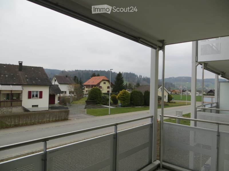 Balcony overlooking a residential area with houses, trees, and a road.
