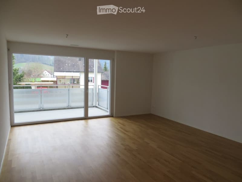 Empty room with wooden flooring and large sliding glass doors leading to a balcony.