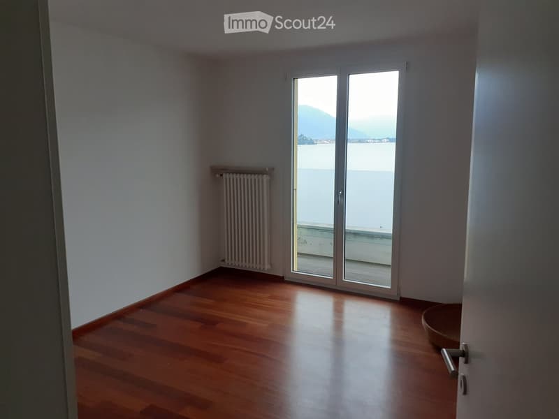 empty room, hardwood floors, sliding glass door, balcony, radiator, open view of water and mountains