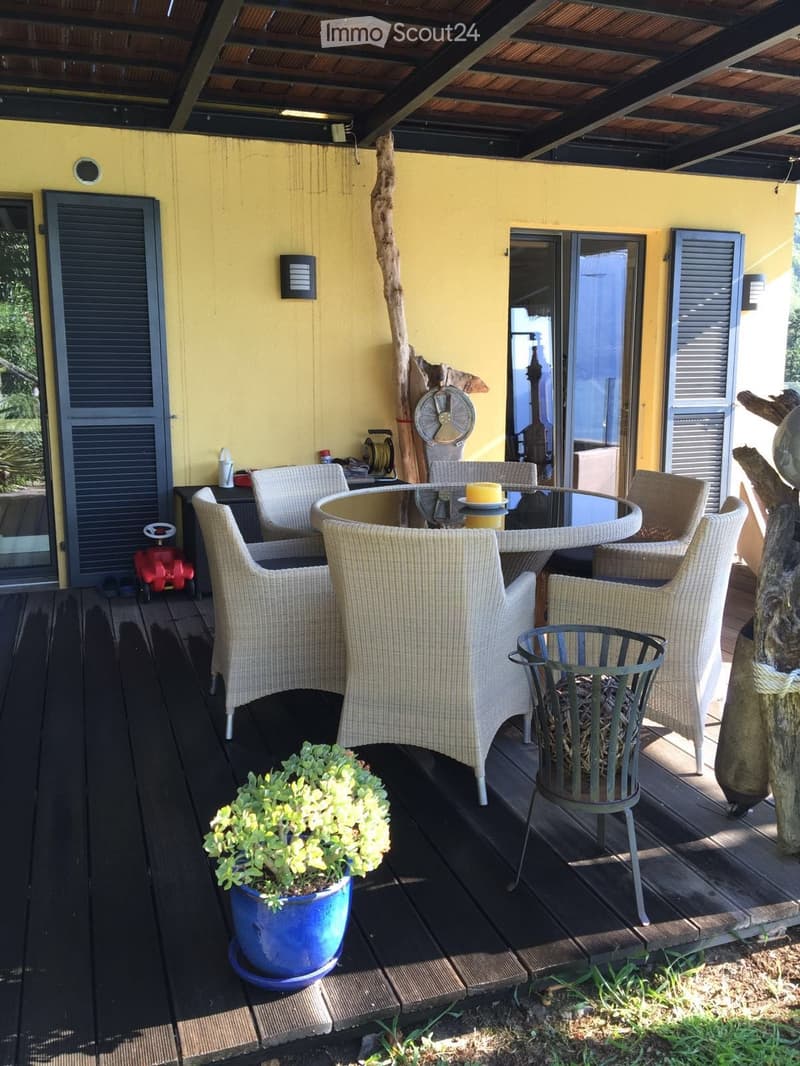covered patio, dining table with chairs, round tray with candle, tree trunk, yellow house
