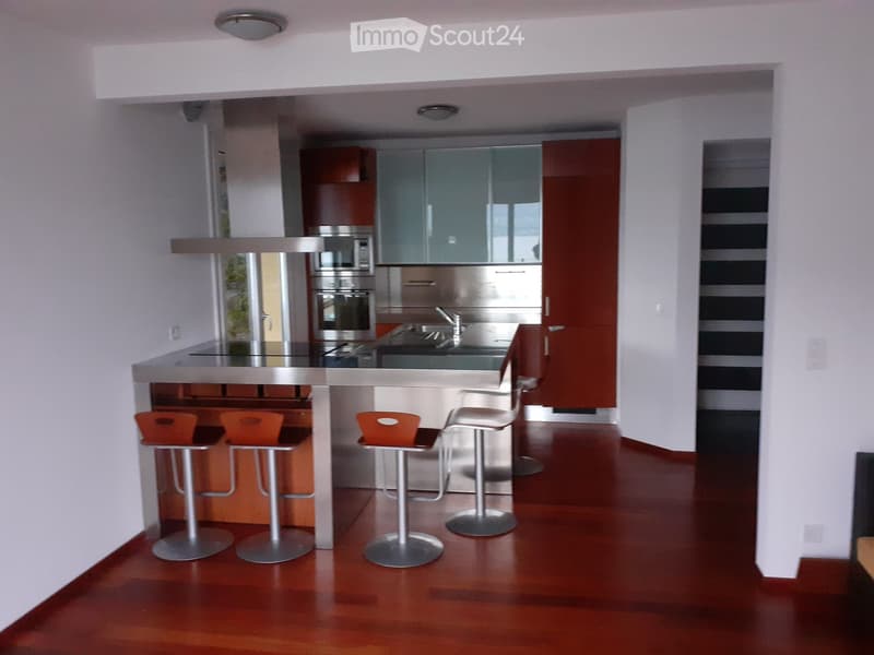 Contemporary open kitchen with wooden flooring, stainless steel island, modern cabinetry, modern appliances, three stools