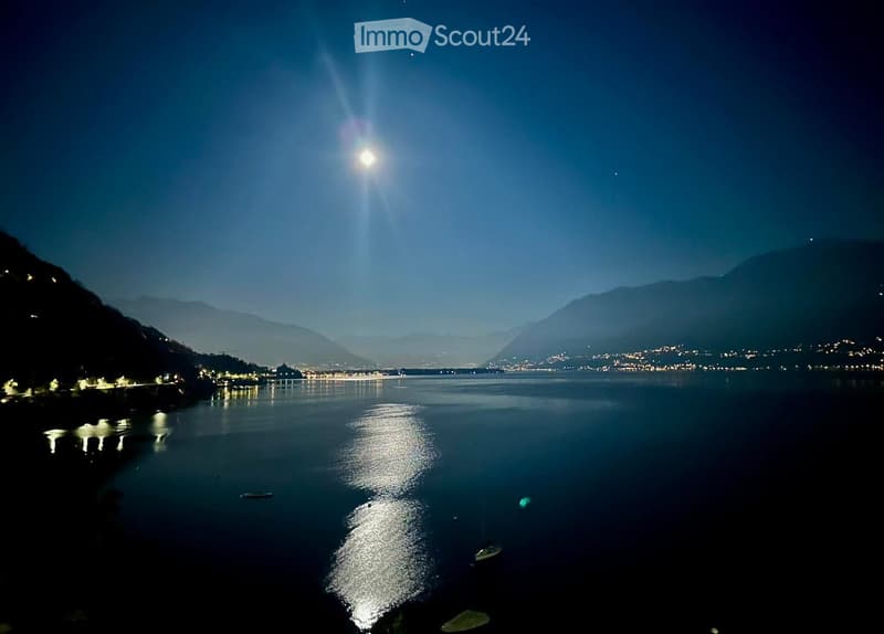 lake at night, full moon, mountains in the distance, city lights
