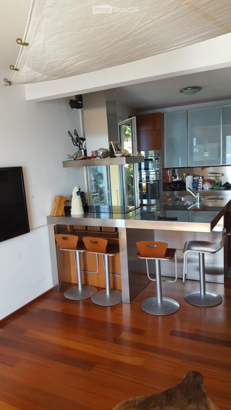 modern kitchen, wooden floor, large countertop, bar stools, stainless steel sink, dishwasher, oven