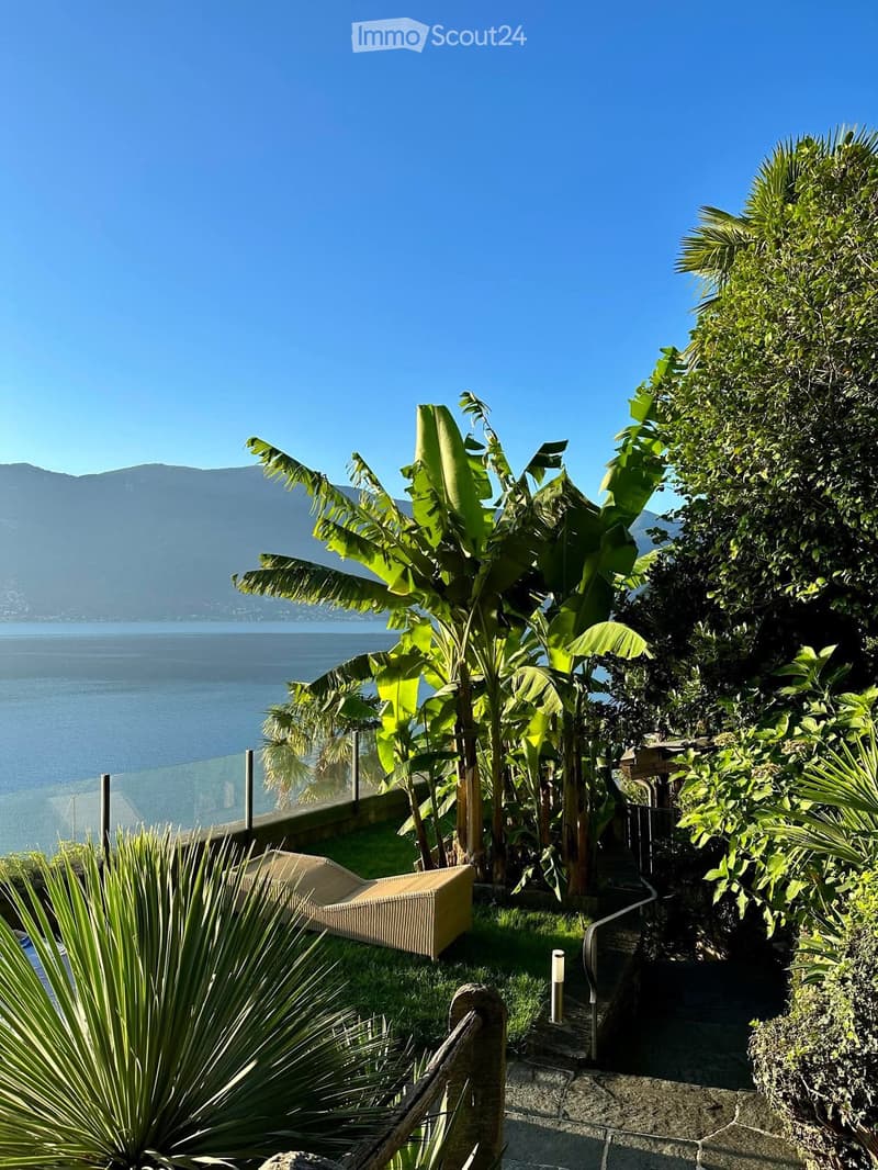 Well manicured lawn, tropical plants, water feature, mountain range, and lake in the distance