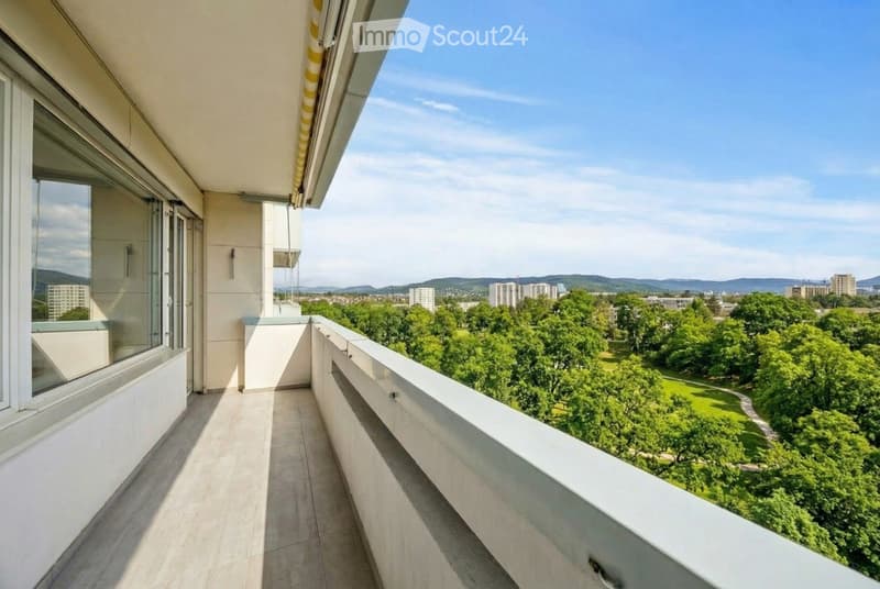 Balcony with tiled flooring, white railing, and a view of a park and cityscape.
