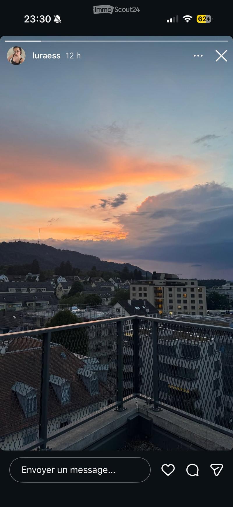 Balcony overlooking a cityscape at sunset, with a metal railing and distant rooftops.