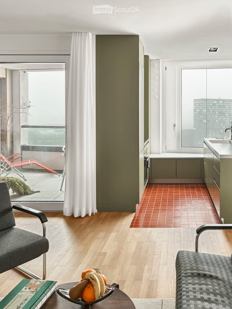 modern living room with wooden floor, large windows, balcony, modern furniture, kitchen area with red tiled floor