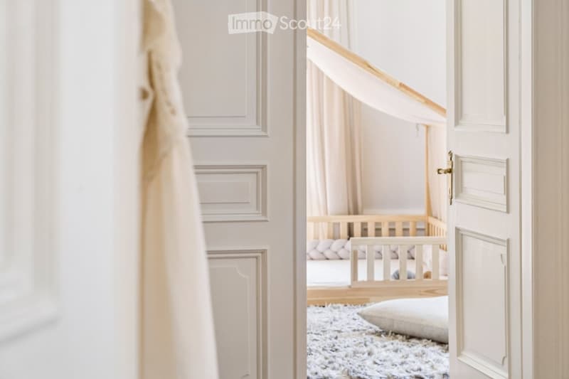 A cozy, well-lit nursery with a wooden crib, soft pillows, and a plush white rug on the floor.