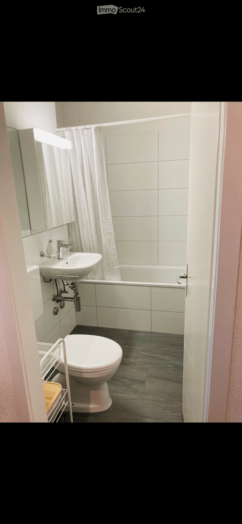 Bathroom with white tiles, bathtub, sink, toilet, mirror, and shower curtain