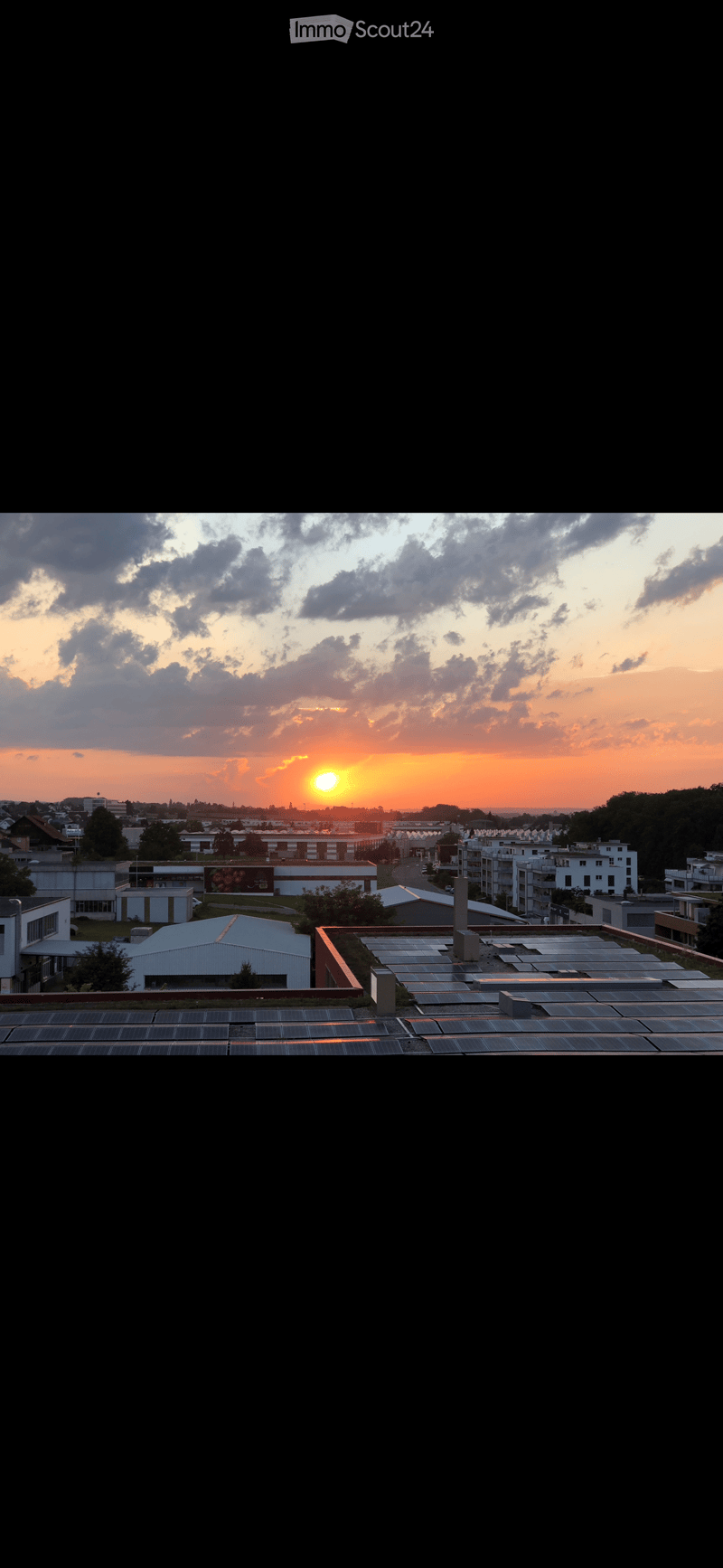 Aerial view of a city with a sunset in the background, solar panels on the rooftop