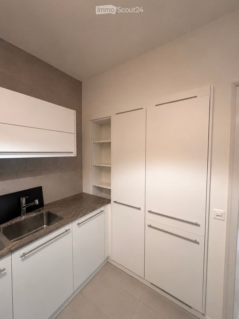 Modern kitchen with white cabinets, wooden countertop, and stainless steel sink.
