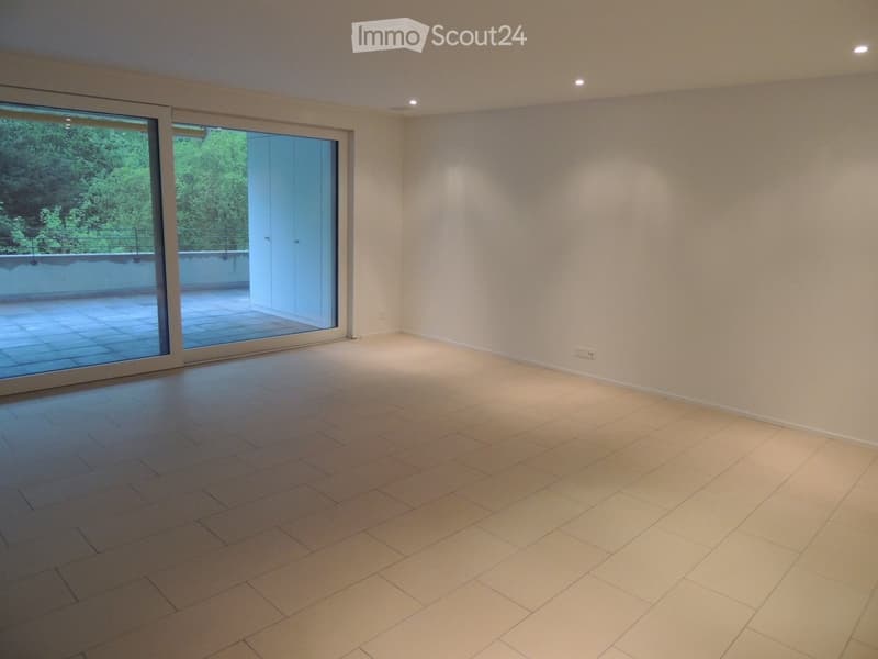 Empty room with light-colored tiled flooring, white walls, and large sliding glass doors leading to a balcony or terrace area.