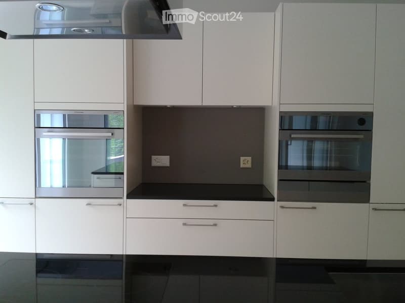 Modern kitchen with white cabinets, stainless steel oven, and black countertops.