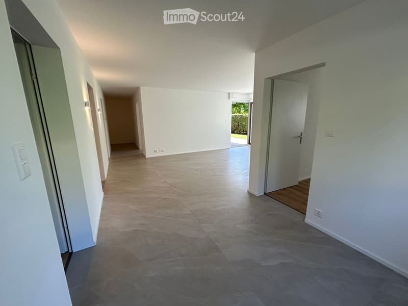 Empty hallway with tiled floor, white walls, and multiple doors leading to other rooms.