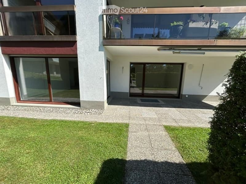 Modern two-story building with balconies, large windows, and a well-maintained lawn.