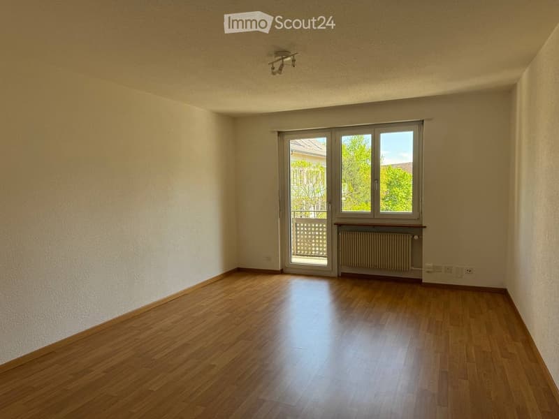 Empty room with wooden flooring, large window with sliding doors, radiator, and ceiling light fixture.