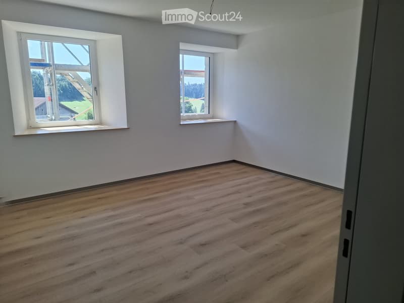 Empty room with wooden flooring and white walls, featuring two windows with white frames and sills.