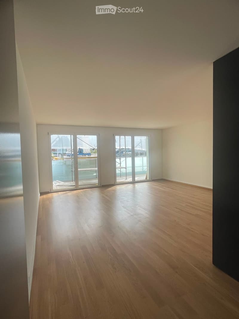 Empty room with wooden flooring and large glass sliding doors leading to an outdoor area.