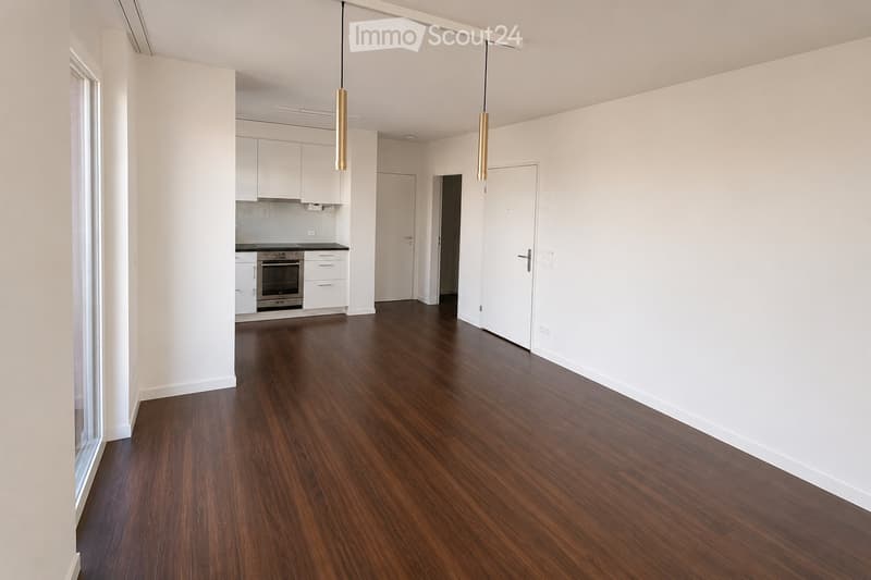 Empty room with wooden flooring, white walls, and white cabinetry in the background. No furniture or personal items are present.