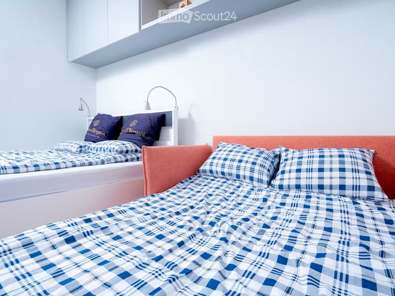 twin bed, sofa bed, blue and white checkered bedding, two nightstands with lamps, white shelves