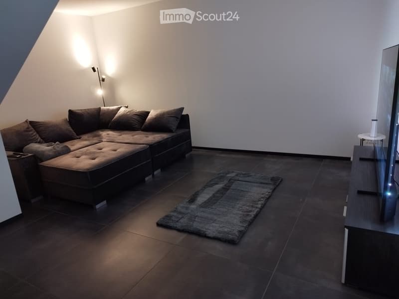 Modern living room with dark brown sectional sofa, coffee table, side table, and a small rug on a dark tiled floor.