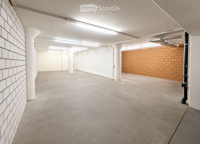 Empty corridor with white brick walls, concrete floor, white pillars, and a mix of white and orange brick sections.