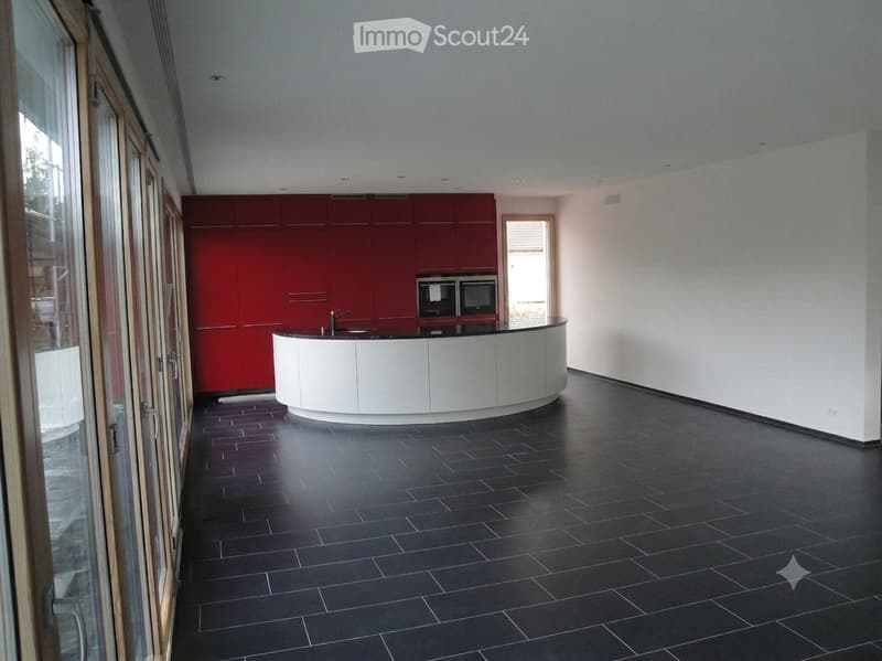 Modern kitchen with red cabinets, white island, black tiled floor, and built-in microwave.
