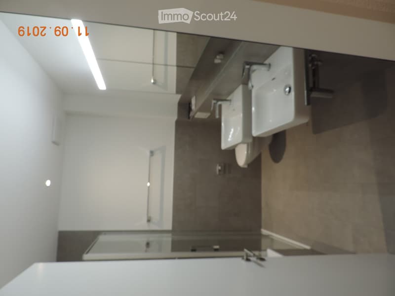 Modern bathroom with a large mirror, double sink, and sleek fixtures.