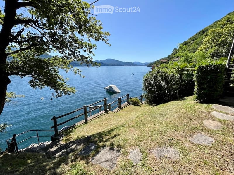 grassy area with steps, wooden fence, lake view, boat