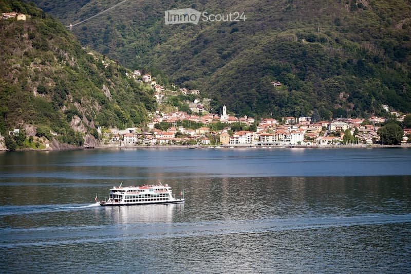 A ferry boat traveling on the water with mountains in the background.