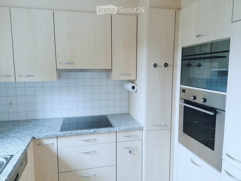 Modern kitchen with white cabinets, granite countertop, induction cooktop, and built-in oven.