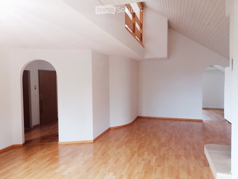 Empty room with white walls, wooden floor, and arched doorways leading to other spaces.