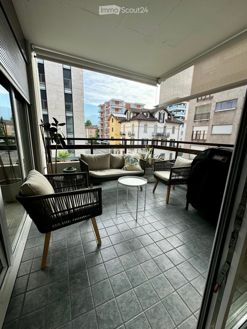 Balcony with tiled floor, sofa, chairs, small table, and potted plants.