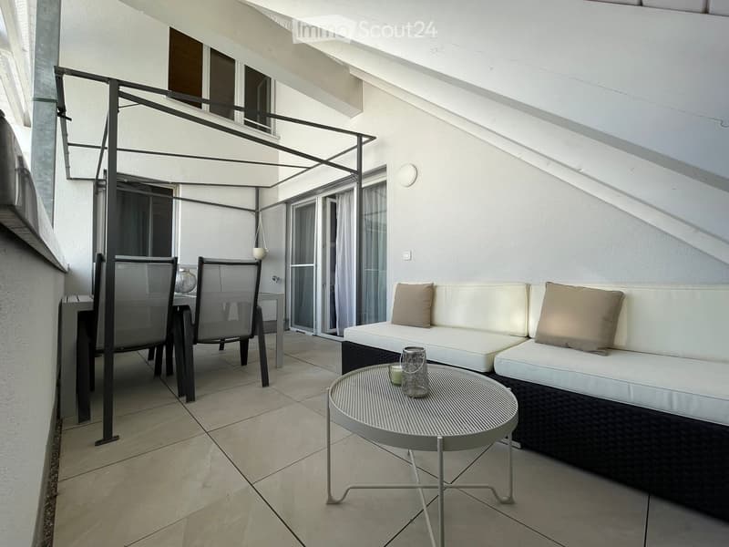 Balcony with a white sofa, small round table, and two chairs, featuring a modern design with a metal frame and a tiled floor.