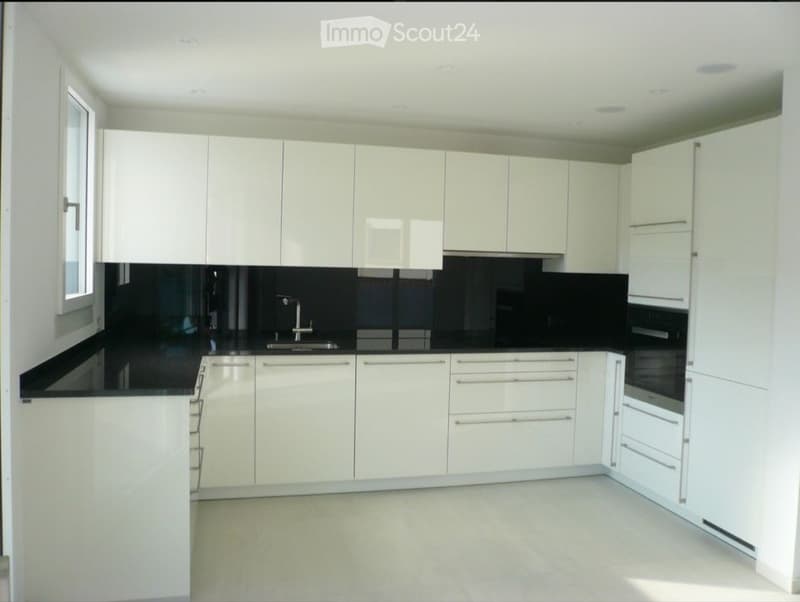 Modern kitchen with white cabinets, black countertops, and stainless steel appliances.