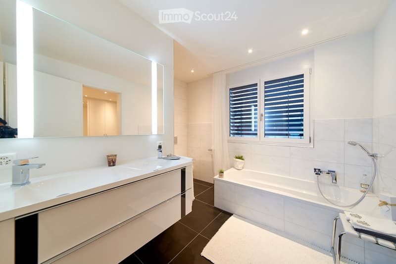 Bathroom, white tile walls, large mirror, bathtub, sink, vanity, and shower area