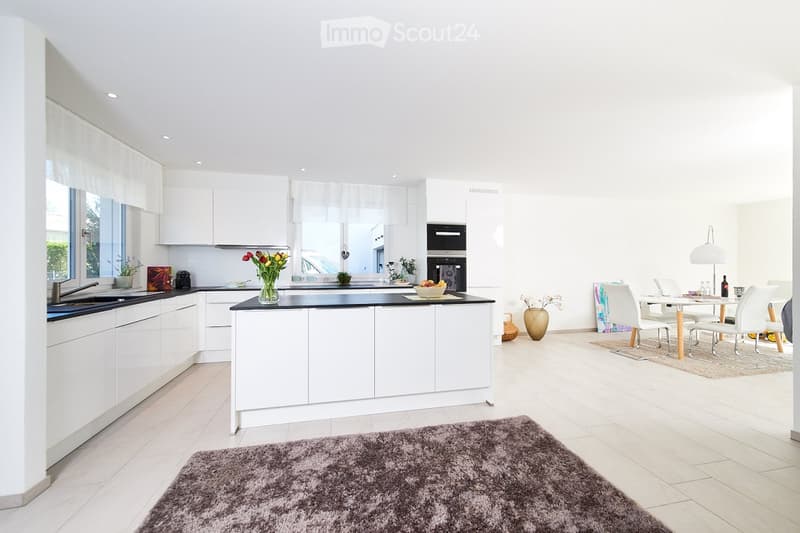 large white kitchen island, black counter, dark rug, dining table with chairs