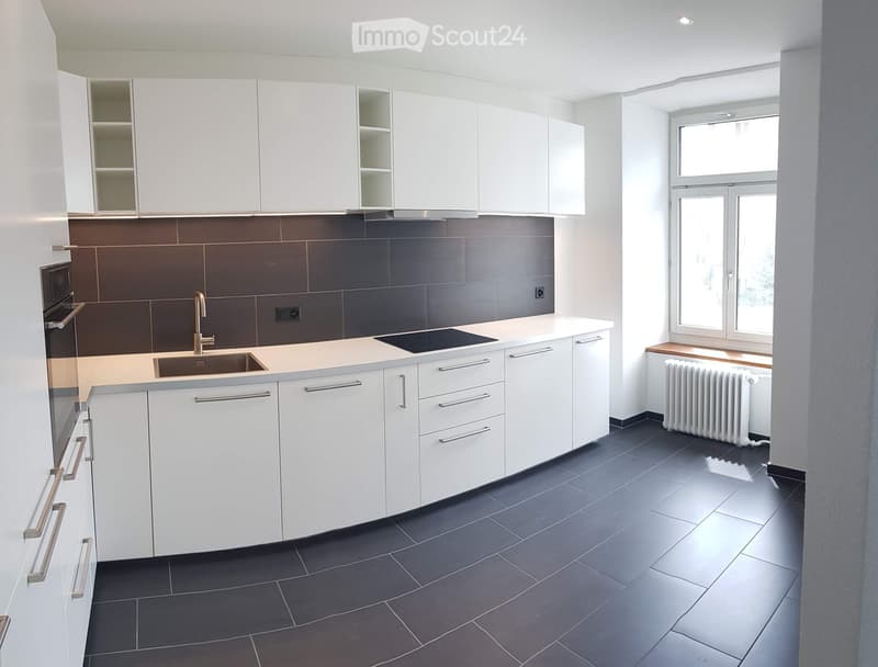 modern kitchen with white cabinets, black tiled floor, gas stove, sink, window with view
