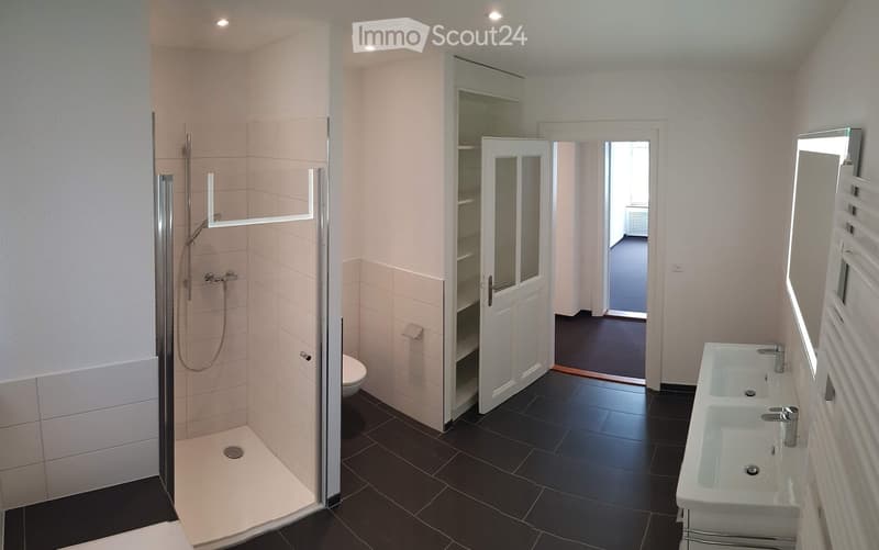 modern bathroom with shower, toilet, double sink, mirror, and tiled floor