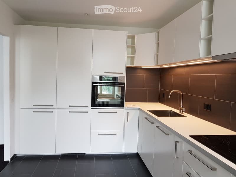 modern kitchen with white cabinets, black tiled floor, integrated oven, sink, faucet, countertop