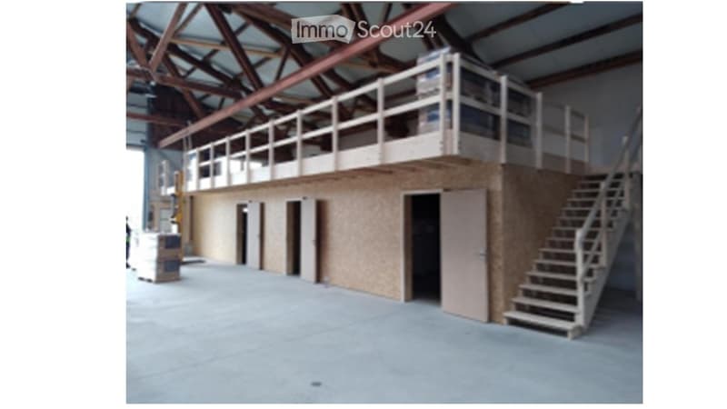 Large industrial-style building with a raised ground floor, metal staircase leading to an upper level, and exposed wooden beams on the ceiling.
