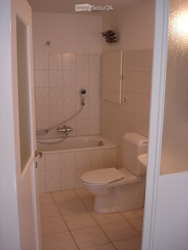 Modern bathroom with a bathtub, toilet, tiled walls, and a showerhead.
