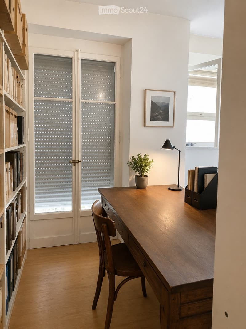 A modern, well-lit study or home office with a wooden desk, a chair, a bookshelf, a lamp, a small plant, and a framed picture on the wall.
