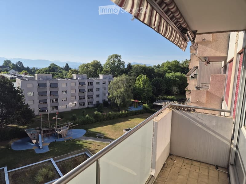 Balcony overlooking a residential area with a playground, grassy area, and surrounding buildings.