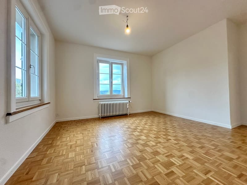 empty room, wooden parquet floor, white walls, two windows, radiator, wooden window sills, ceiling lamp