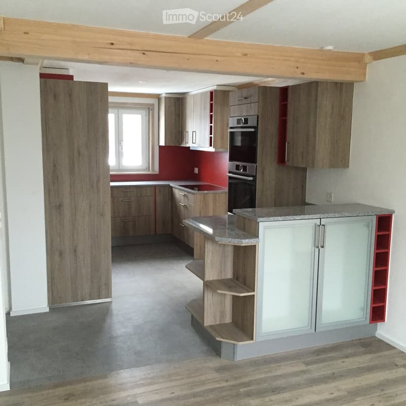 Modern kitchen with wooden cabinets, stainless steel oven, island with granite countertop, and open shelving.