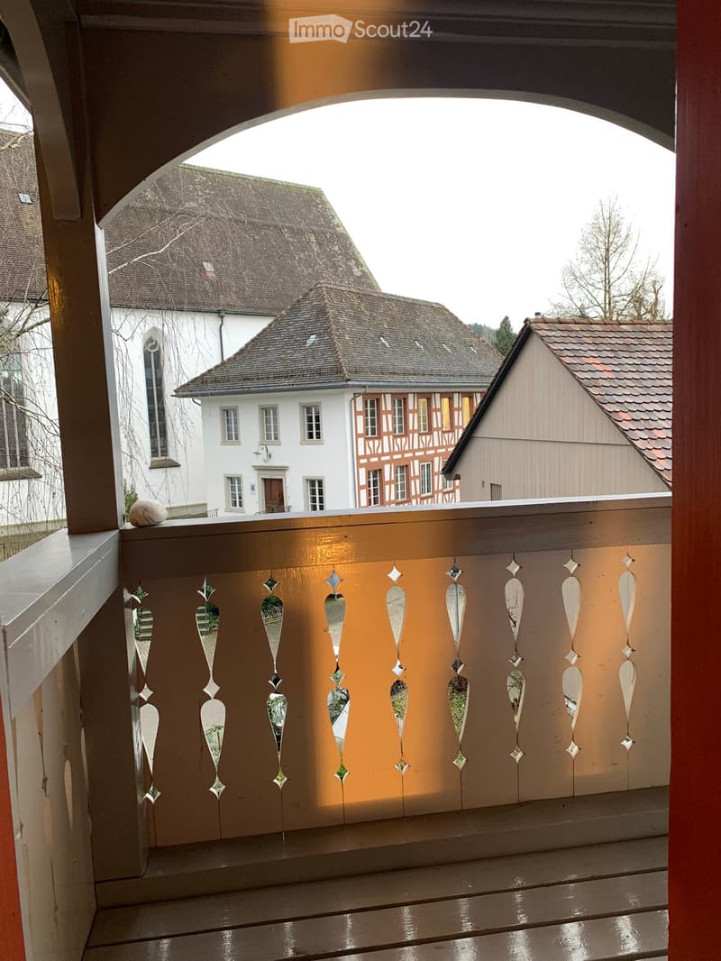 Balcony with wooden decking, decorative glass ornaments, and a view of traditional houses in the background.
